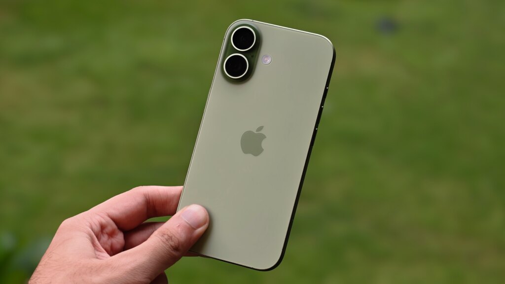 Apple Might Skip the iPhone 18 This Year. Is the iPhone 17 Still Worth It? Prakhar holding the Apple iPhone 17 against a green garden background.