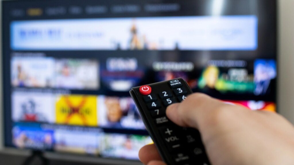 Nahaufnahme einer Fernbedienung die auf einen TV gerichtet ist