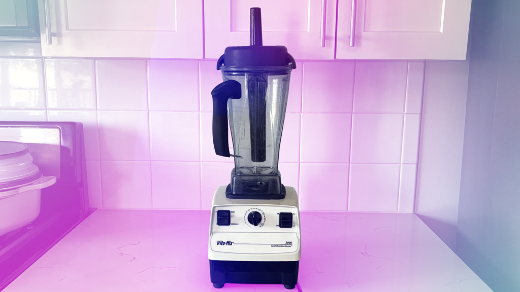 I Tested My 19-Year-Old Vitamix Against Brand-New Models. Here’s Who Won The white Vitamix 5000 with a transparent pink and blue gradient background.