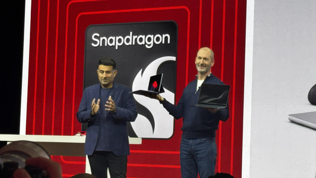 Microsoft’s New Surface Laptops Embody the PC-Phone Marriage Snapdragon Promised Years Ago Two men stand on stage, one clapping while another holds two laptops up.