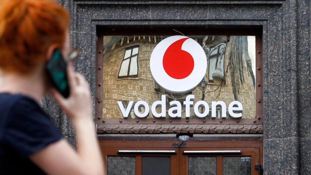 Vodafone-Logo an einer Wand, links davon eine Person wie sie telefoniert