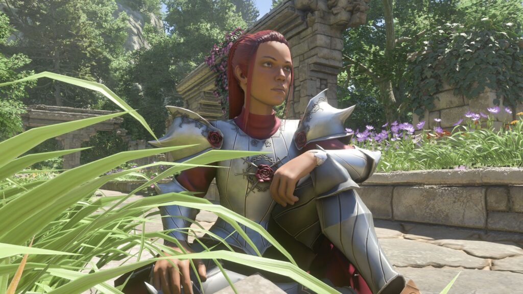 Enshrouded player character with red hair in silver knight-like armor sitting on a stoney path with flowers