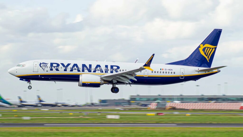 A Ryanair airplane flying low above a runway.